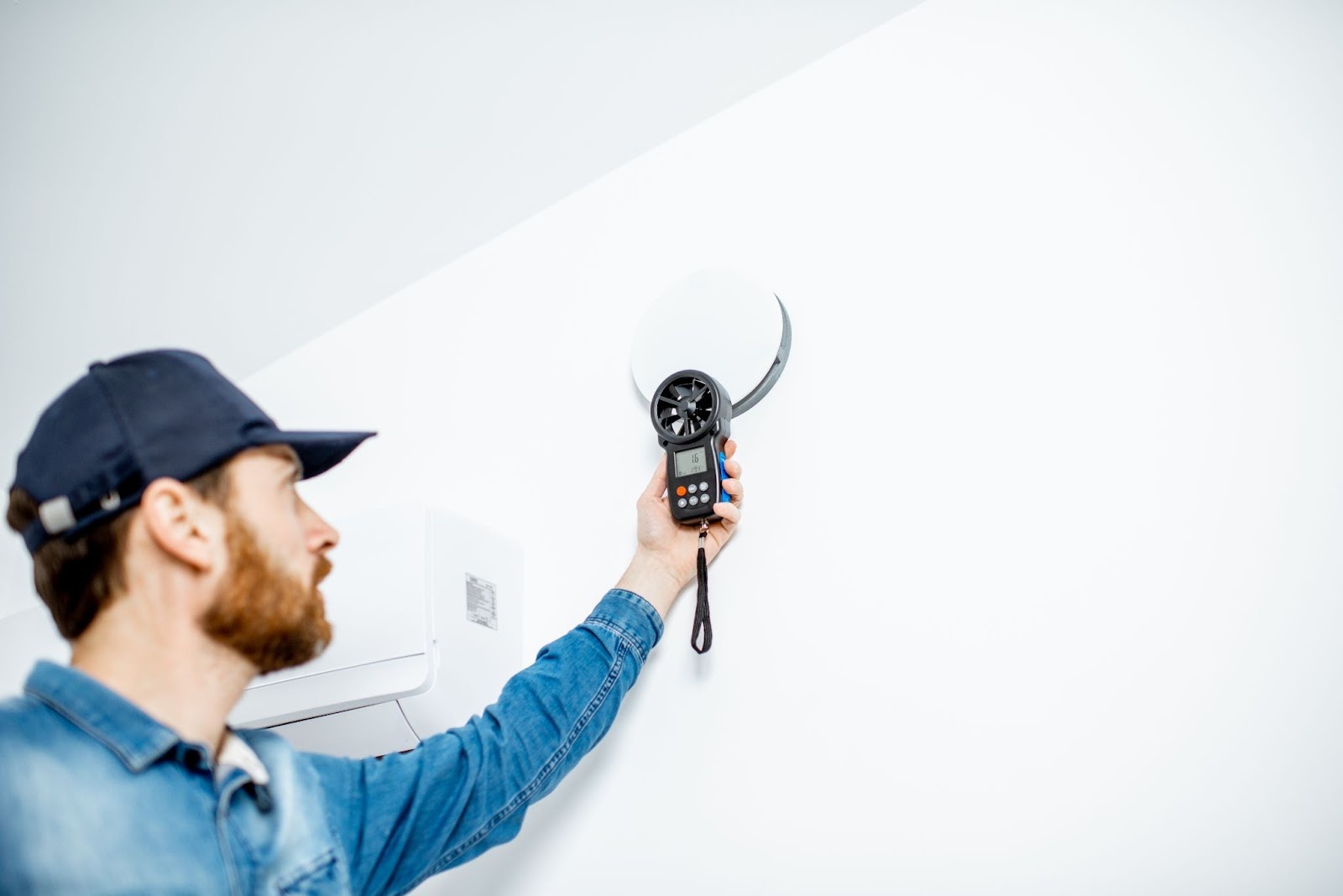 Alt-text: A technician checks the air quality readings next to a carbon monoxide alarm on the wall.