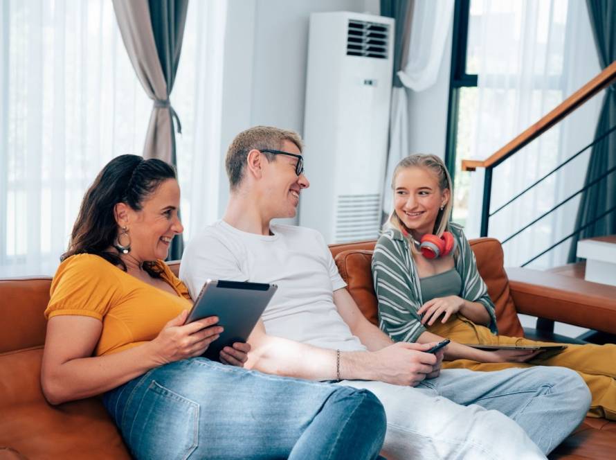 A happy family relaxing on the couch enjoys the cool air from a split-type HVAC system