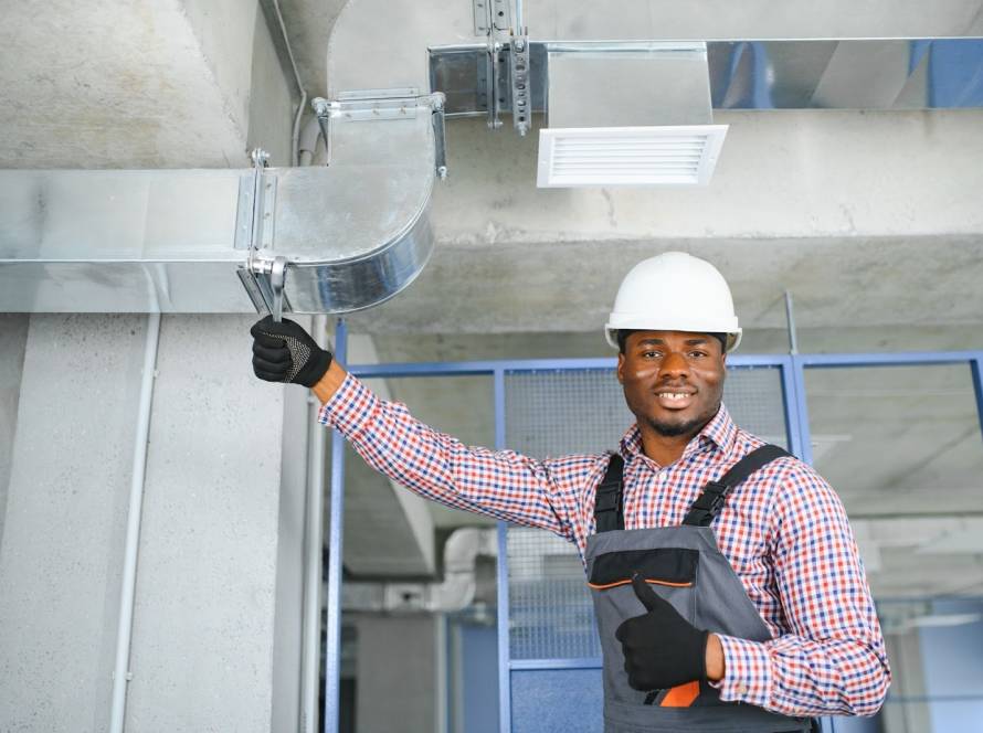 HVAC technician working on a home ventilation system during a service visit